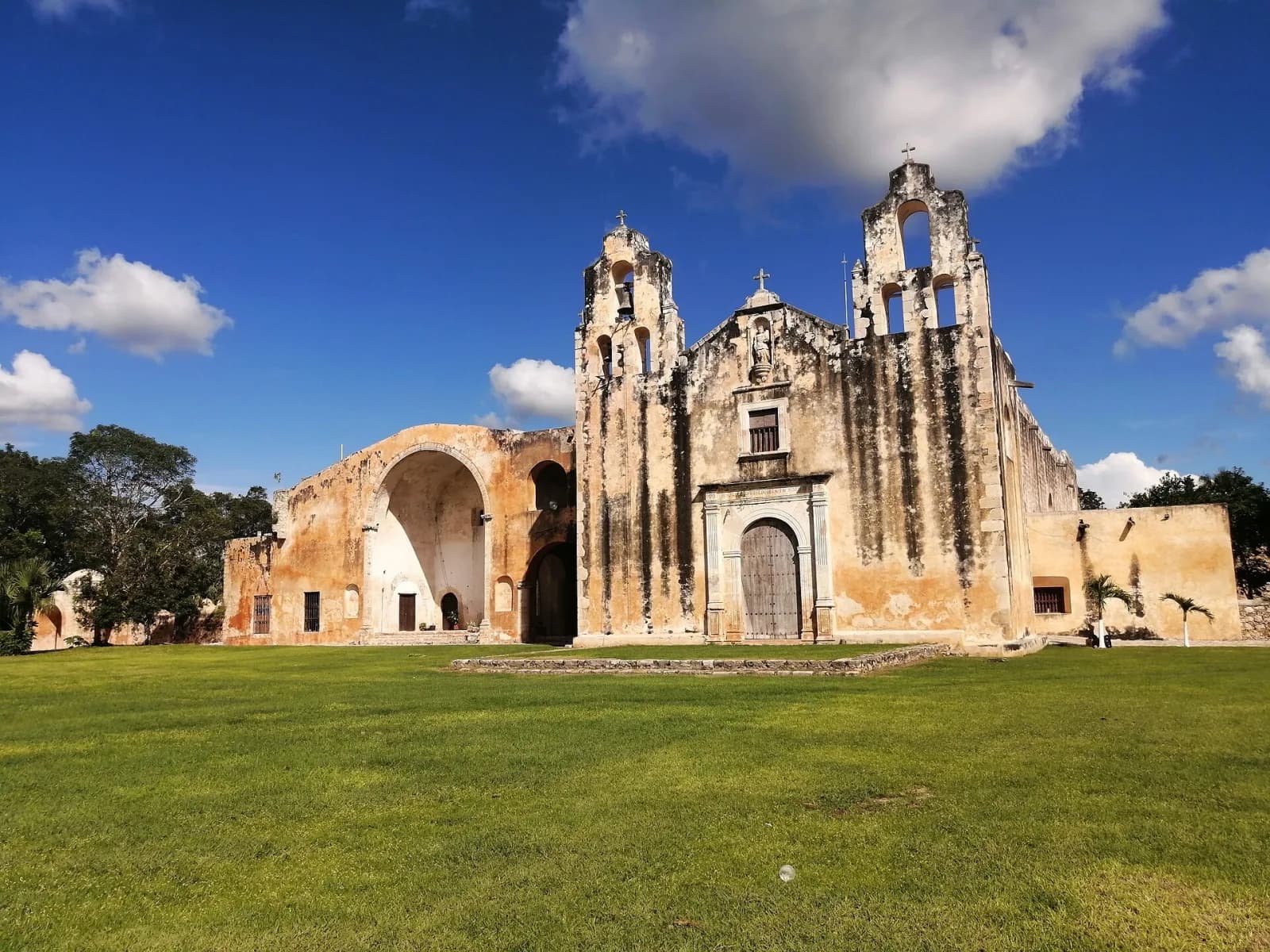Fachada del exconvento de San Miguel Arcángel en Maní, Yucatán, con su capilla abierta y el atrio de pasto