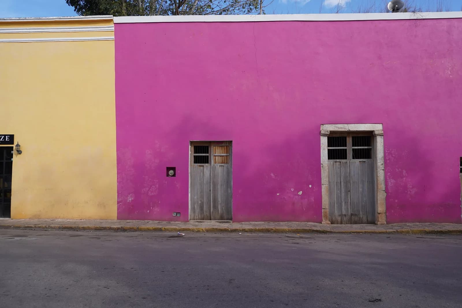 Fachadas rosa y amarilla con puertas de madera en una calle de Maní, Yucatán