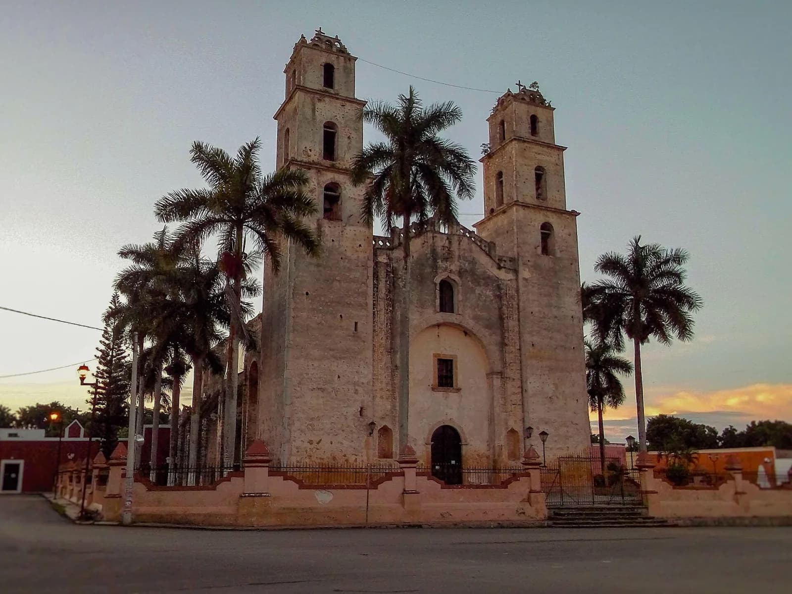 Iglesia de San José de Espita al atardecer, vista en diagonal con palmeras a los lados