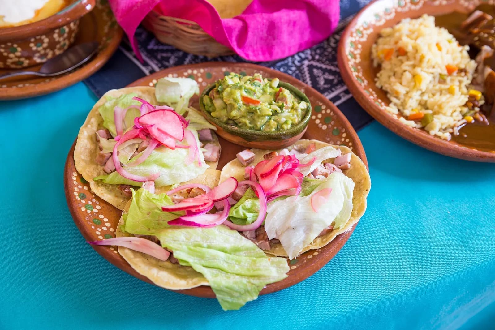 Tostadas con lechuga, cebolla morada y guacamole en plato de barro, Yerbabuena del Sisal